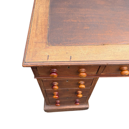 Right pedestal of mahogany desk showing three drawers and turned knobs