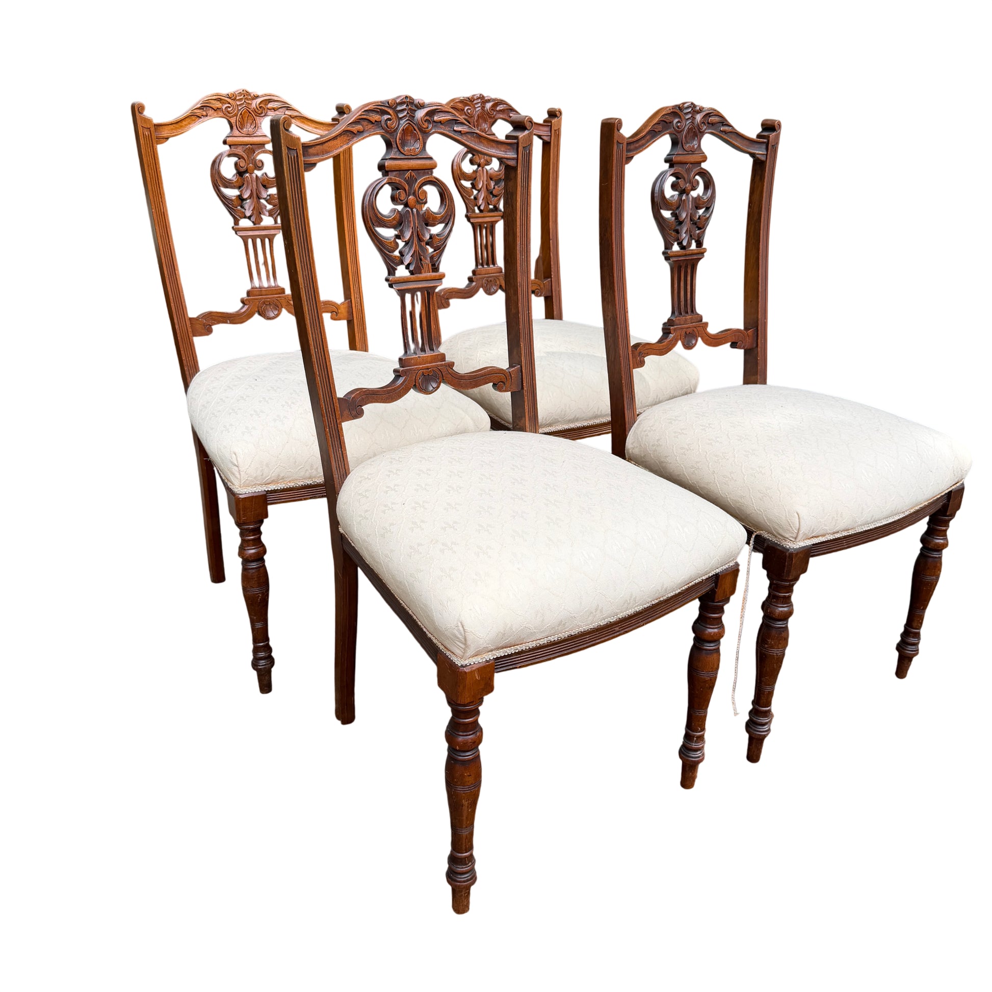 Set of four Edwardian carved dining chairs with cream upholstered seats and pierced carved wooden backs