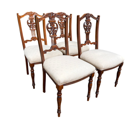 Set of four Edwardian carved dining chairs with cream upholstered seats and pierced carved wooden backs