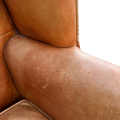 Seat cushion close-up showing crackled leather, surface marks and a tear at the edge
