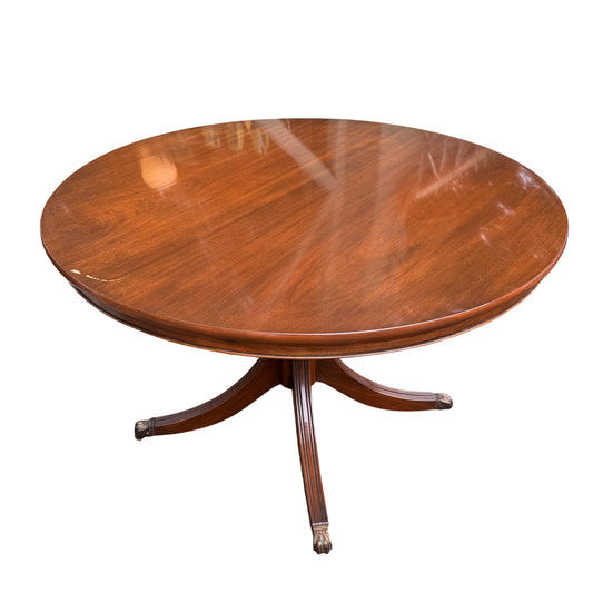 Contemporary round mahogany-veneer dining table on a central pedestal with brass-capped scroll feet