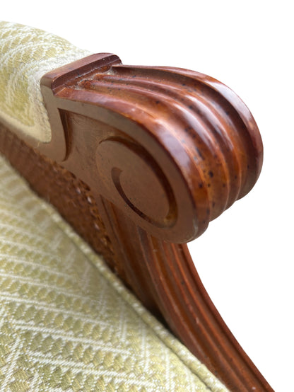 Front view of upholstered cane armchair with carved scrolled arms