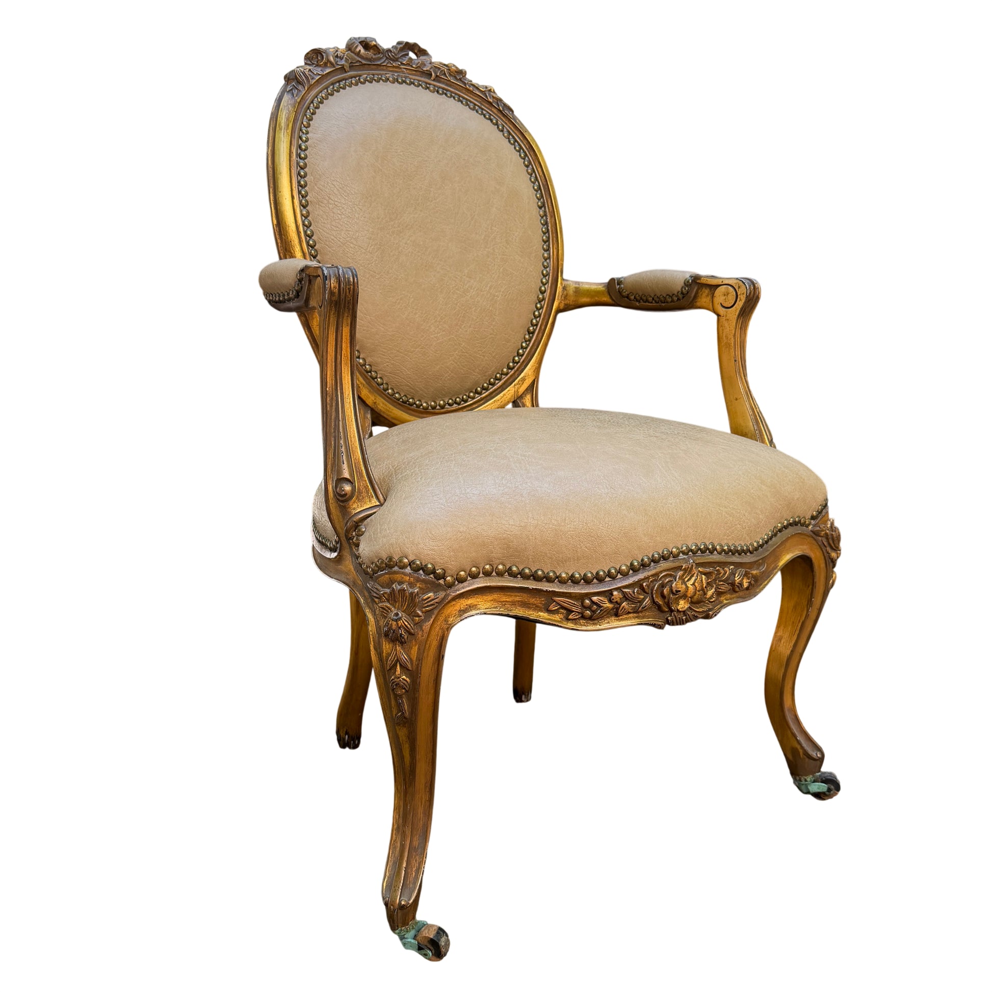 Close-up of oval back on gilt Louis-style armchair showing faux leather upholstery and decorative studs