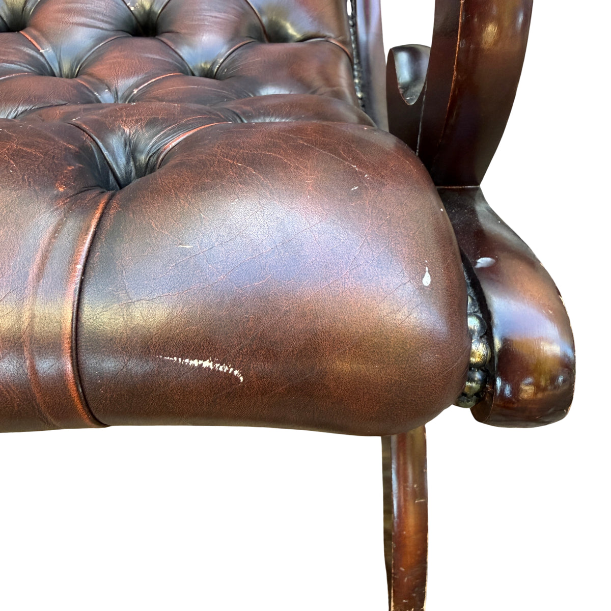 Tufted leather slipper chair showing brass nailhead trim and buttoning