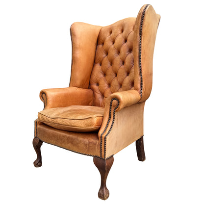 Deep button-tufted backrest on a vintage leather Chesterfield-style wingback chair
