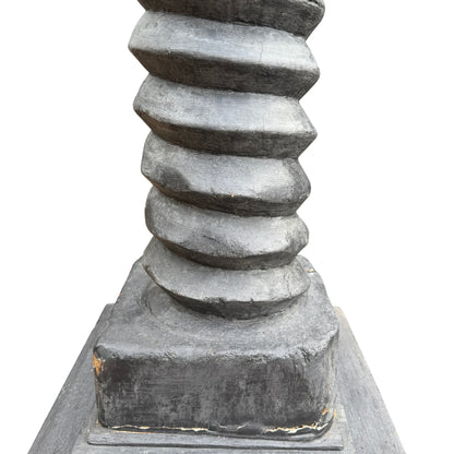 Decorative pedestal stand showing stepped base and square top in charcoal black
