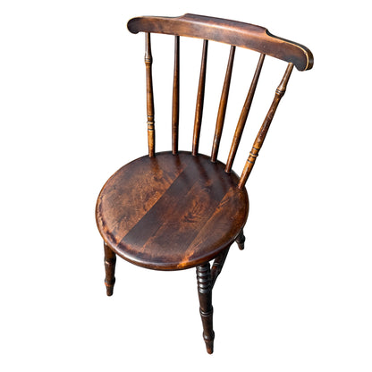 Side view of vintage wooden penny seat chair showing worn finish and edge wear
