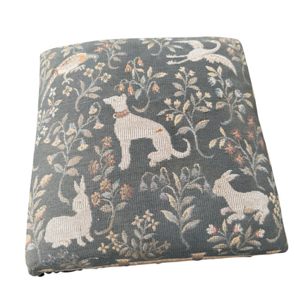 Corner view showing studded trim and tapestry pattern on upholstered footstool