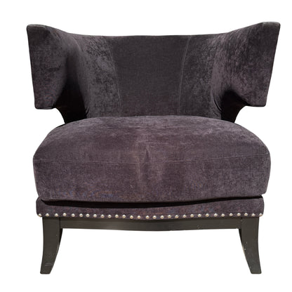 Front corner of upholstered armchair showing removable seat cushion and stud detail
