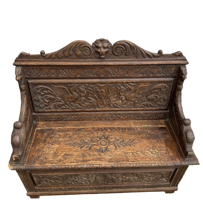 Full view of carved oak monks bench with storage in aged dark finish