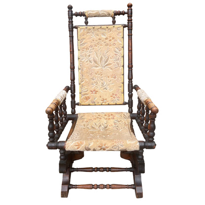 Front view of Victorian rocking armchair with brass nailhead trim and turned spindles