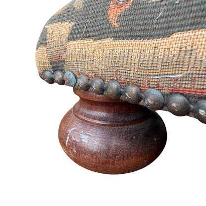 Edge of footstool showing decorative nails and woven tapestry upholstery