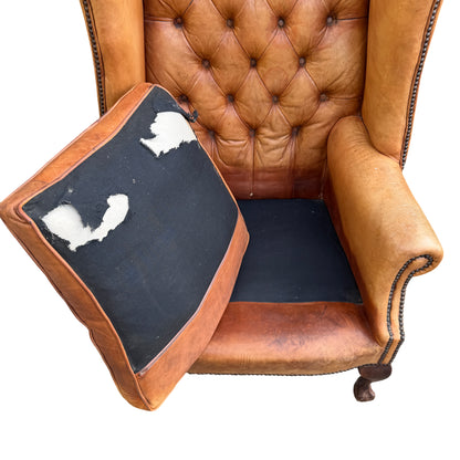Removable seat cushion and lower leather apron on a vintage tan leather armchair