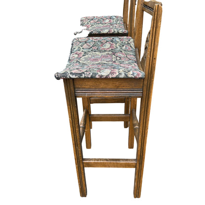 Tall oak bar stools showing turned footrest and scuffed legs