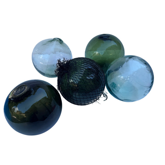 Set of five vintage hand-blown glass fishing floats in sea-green pale aqua and dark olive, one with original netting