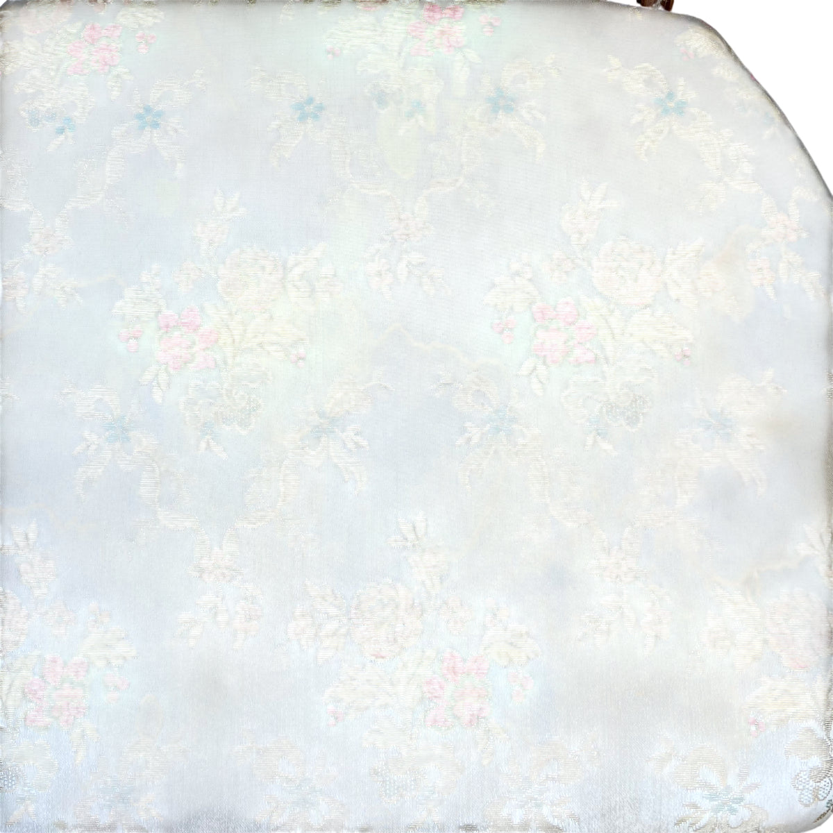 Worn floral upholstery on seat of vintage bergère armchair showing water marks and staining
