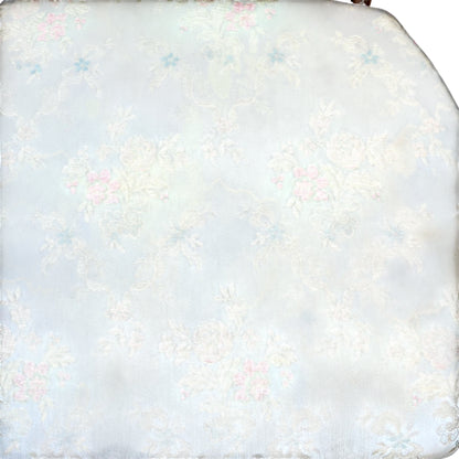 Worn floral upholstery on seat of vintage bergère armchair showing water marks and staining
