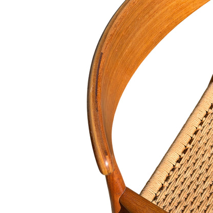 Three-quarter view of teak dining chair showing tapered front legs and seat