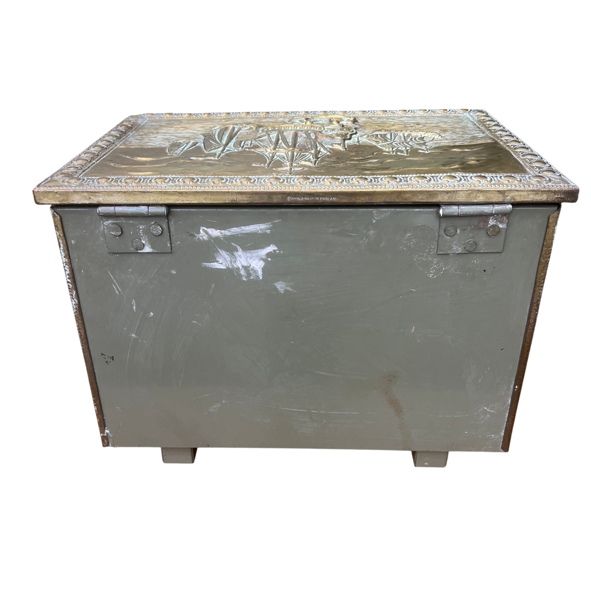 Edge detail of brass lid showing wear and rubbed finish on a decorative chest
