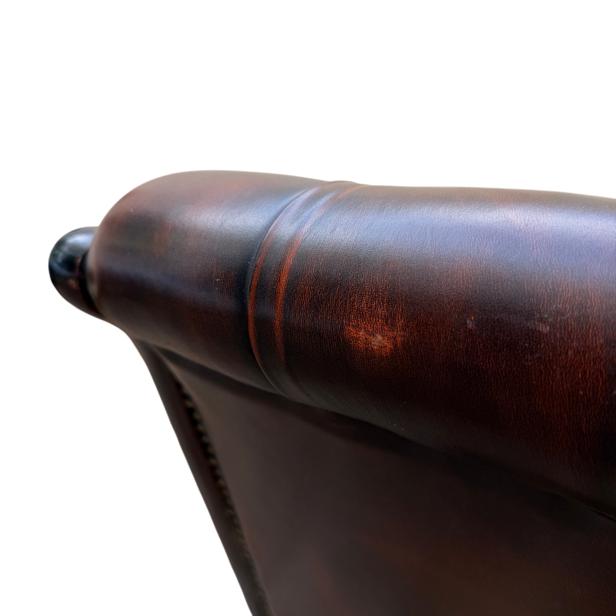 Pair of curved wooden legs and stretcher beneath a brown leather armchair