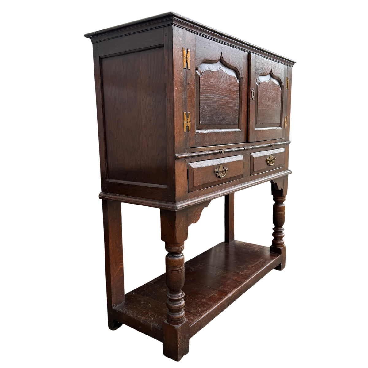 Two-door oak cupboard on stand with brass handles and turned front legs