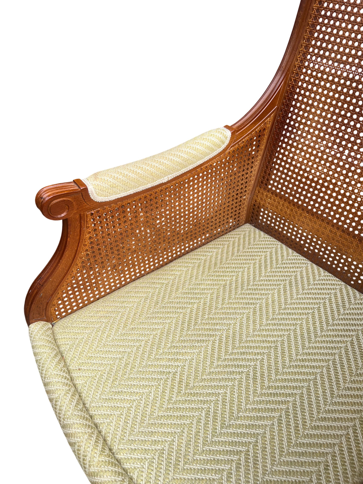 Cane panel side and carved leg of vintage upholstered armchair