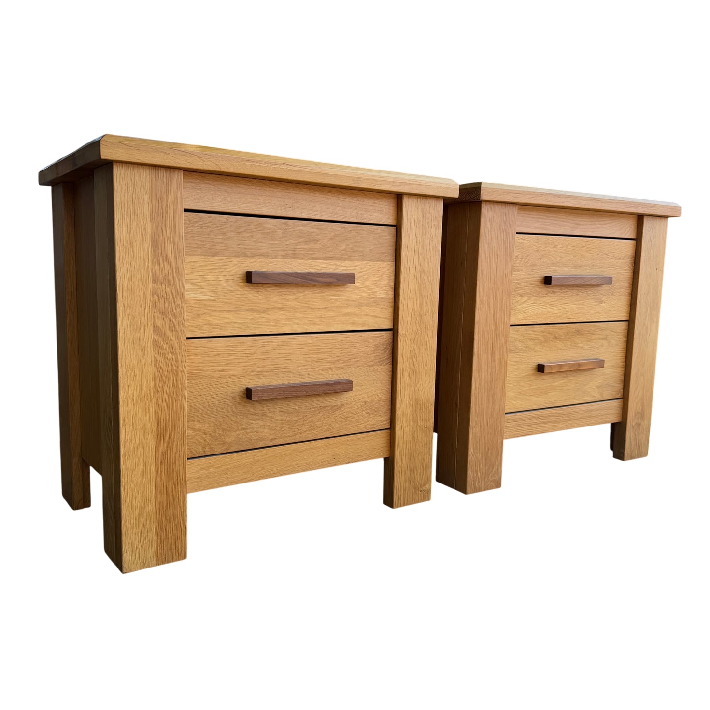 Pair of contemporary solid oak bedside cabinets with darker wood handles shown outdoors