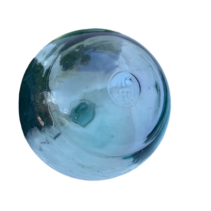 Close-up of vintage glass float with original black rope netting and wear