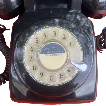 Top view of black rotary telephone showing dial and handset cradle