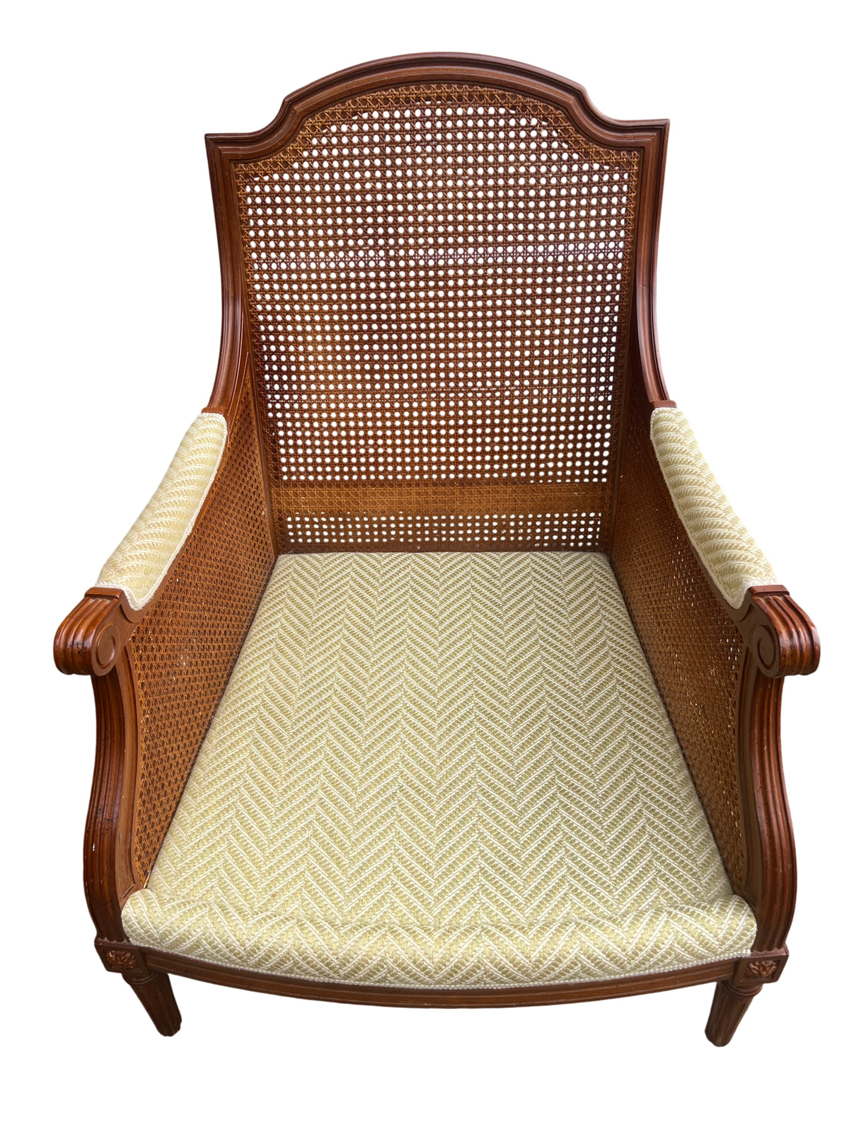 Close-up of pale yellow patterned upholstery on cane armchair