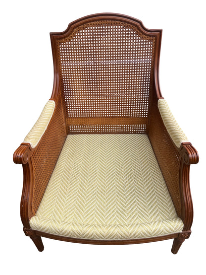 Close-up of pale yellow patterned upholstery on cane armchair
