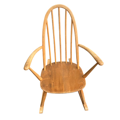 Light-toned wooden Windsor-style rocking chair with spindle back and curved rockers