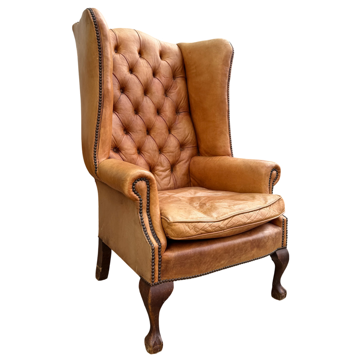 Vintage tan leather Chesterfield-style wingback armchair with deep buttoned back and studded trim