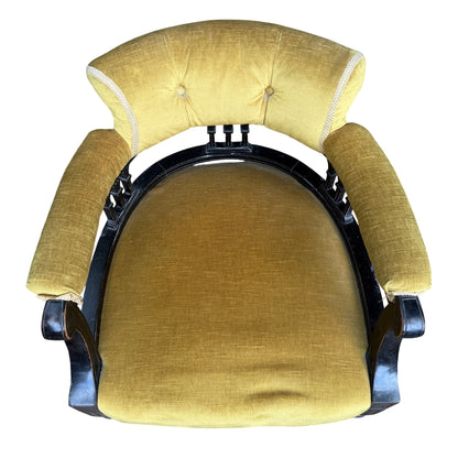 Side view ebonised armchair with rolled arms and turned front legs on ceramic castors