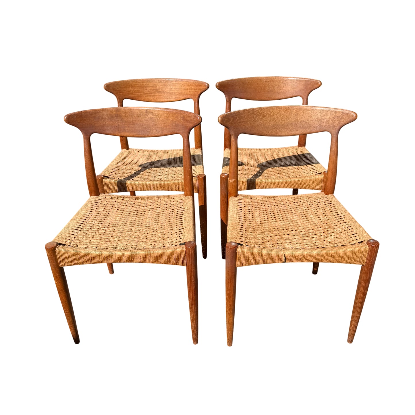 Front view of two teak Danish dining chairs with curved backrests and woven seats