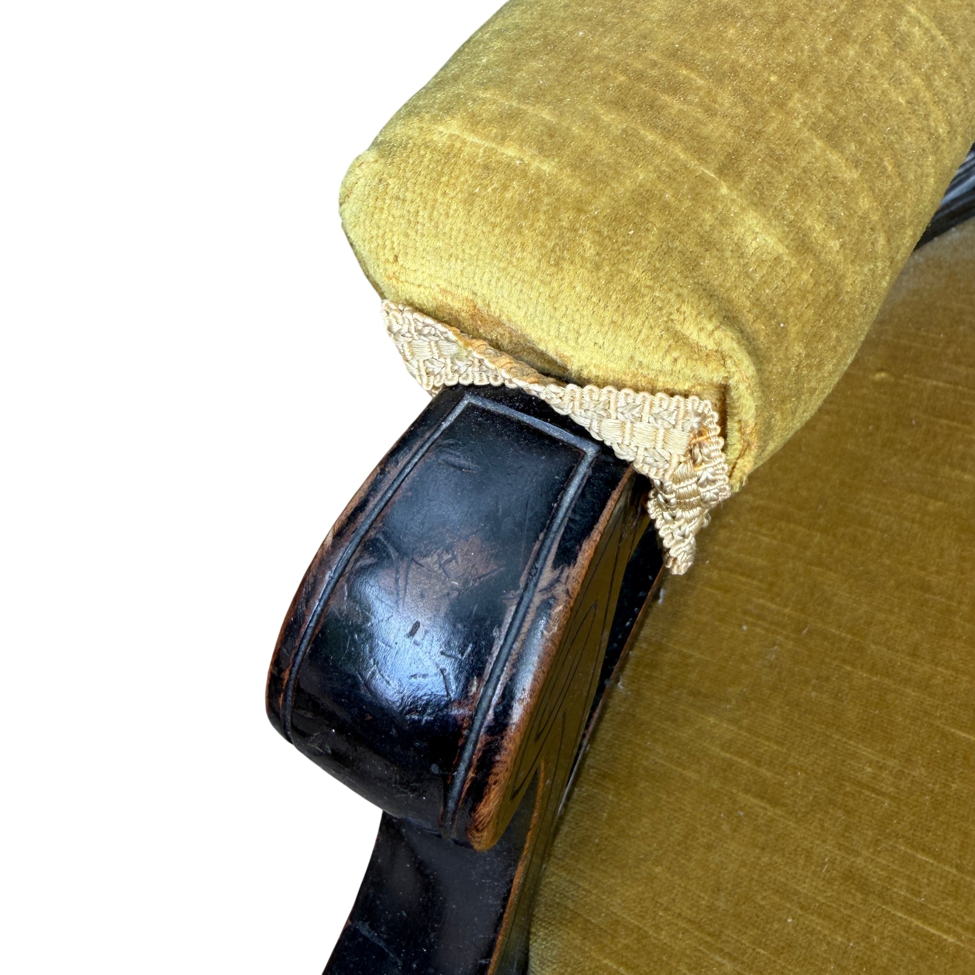 Close-up of rolled arm with decorative trim on upholstered Victorian armchair