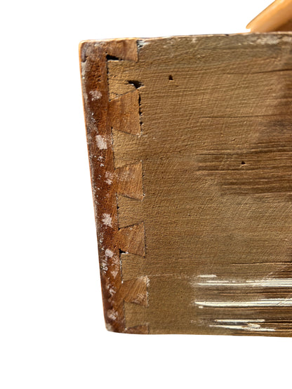 Turned front leg with small caster beneath a pine chest of drawers