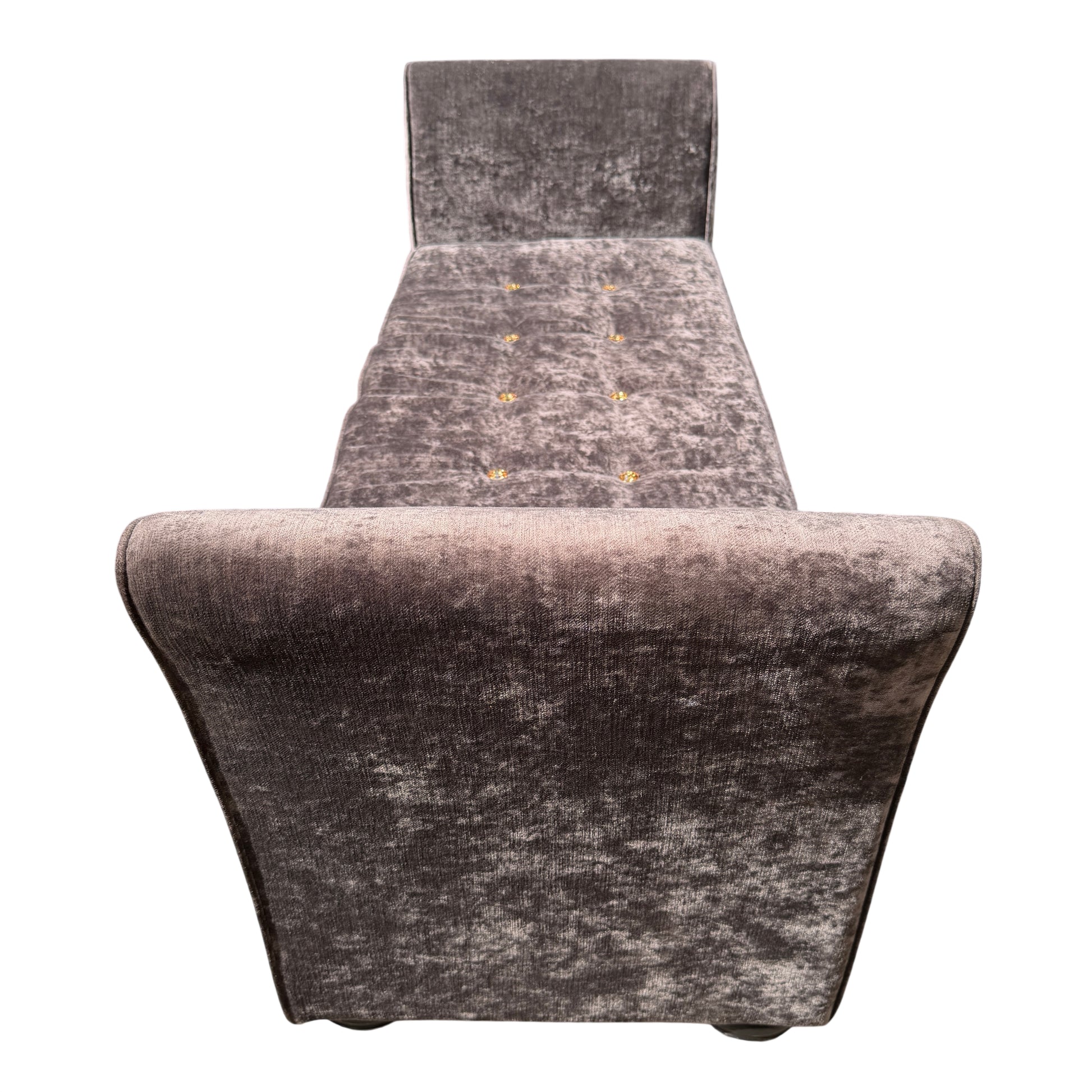 Button tufting detail on the seat of a grey velvet chaise longue daybed