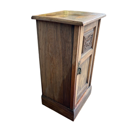 Close-up of carved central panel on a narrow oak bedside cabinet