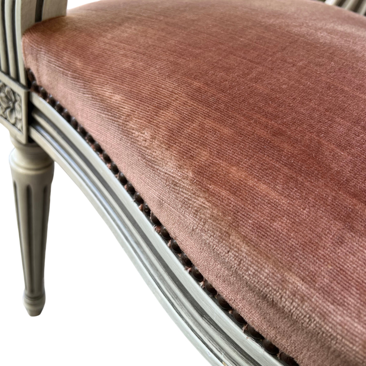 Three quarter view of a painted frame armchair with oval back and nailhead trim