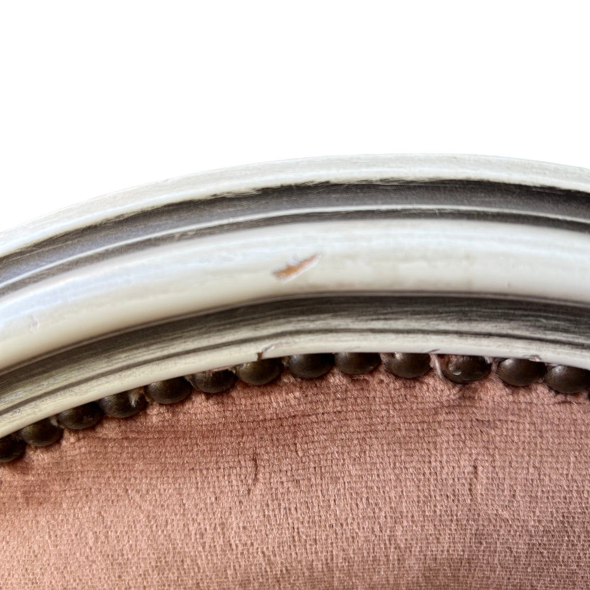 Detail showing paint loss and scuffs on the wooden frame of a vintage upholstered chair