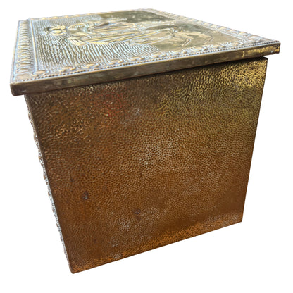 Front panel of vintage brass chest showing raised ship decoration and beaded border
