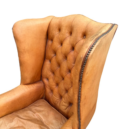 Full-height view of tall winged back on a vintage tan leather armchair