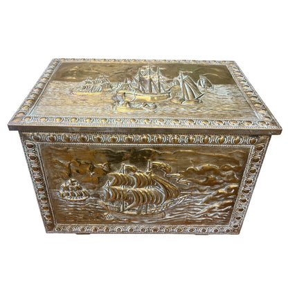 Close-up of embossed sailing ships on the lid of a vintage brass storage chest