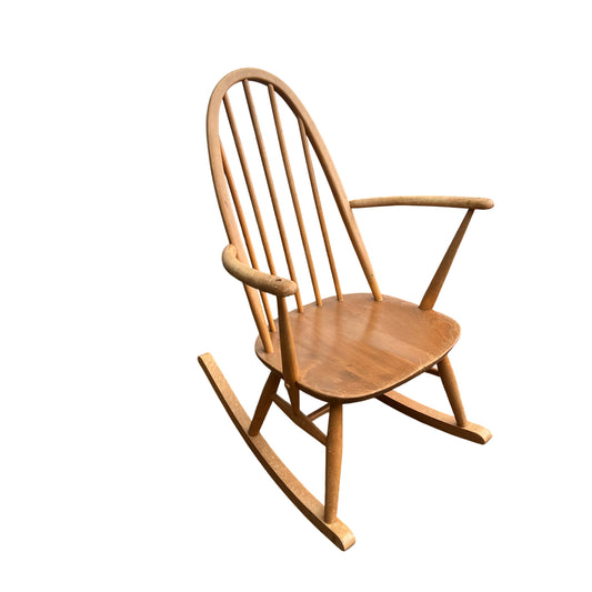 Vintage spindle-back wooden rocking chair with arched top and turned spindles in a light wood tone