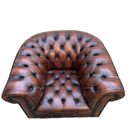 Close-up of studded nailhead trim and rolled arm on a brown leather Chesterfield armchair