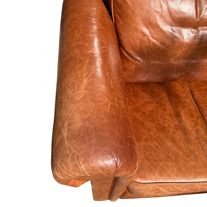 Leather surface close-up showing natural creasing and patina on cognac sofa