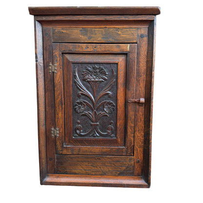 Carved floral panel on oak corner wall cabinet in Arts & Crafts style