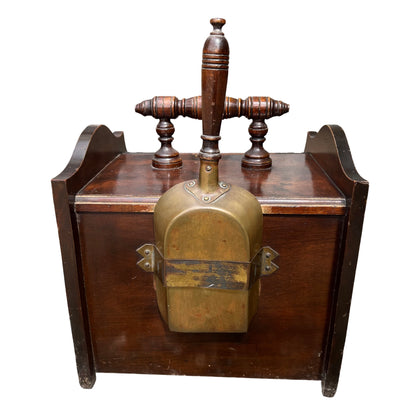 Brass shovel and wooden handle resting in the coal scuttle interior with tin liner visible