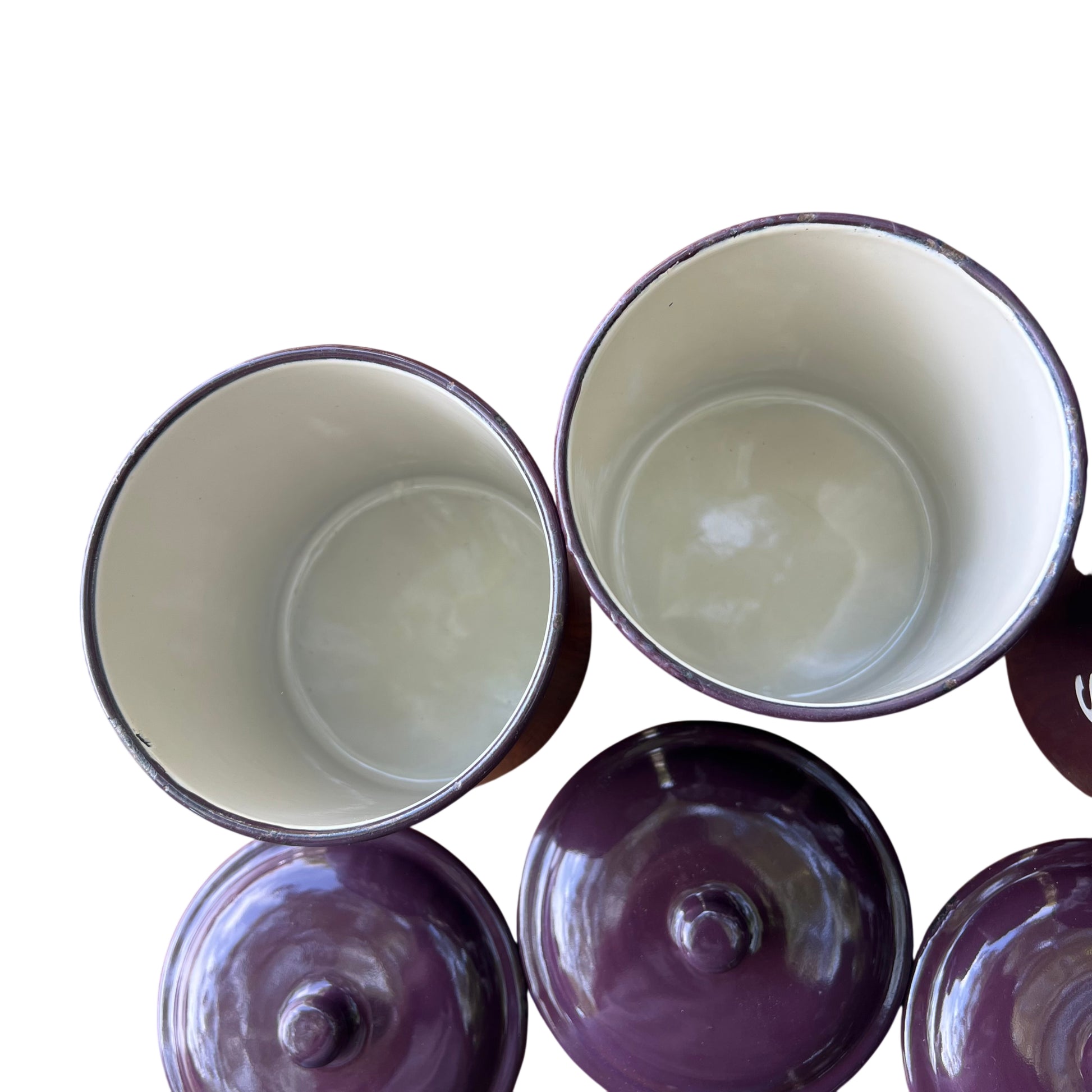 Close-up of enamel canister lids showing reflective glaze and fitted knobs